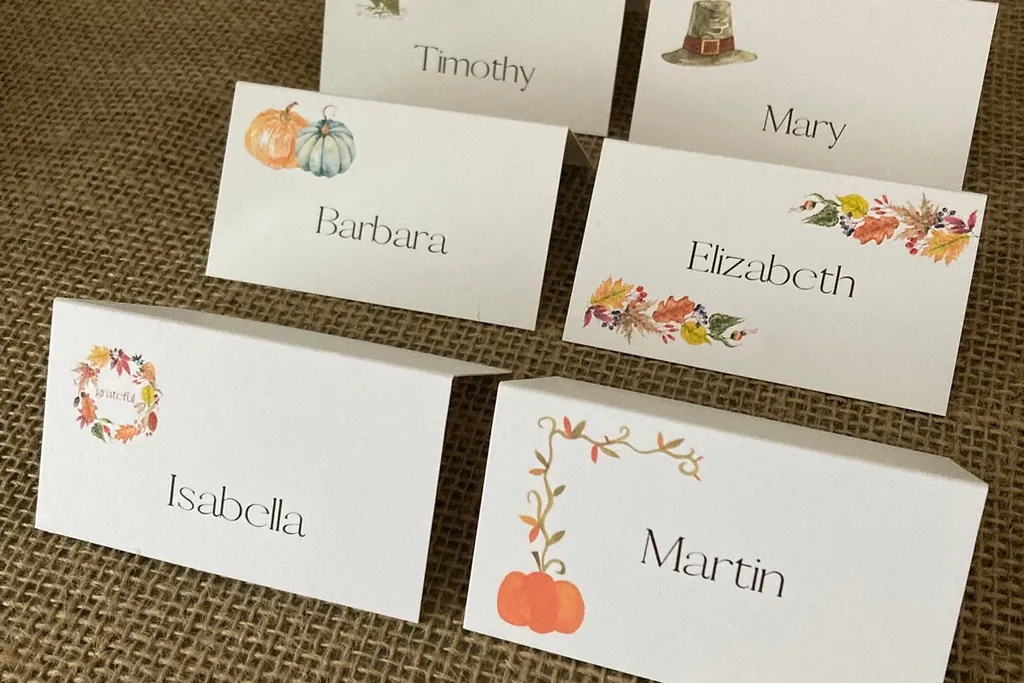 Handwritten tent place cards with guest names and small fall designs.