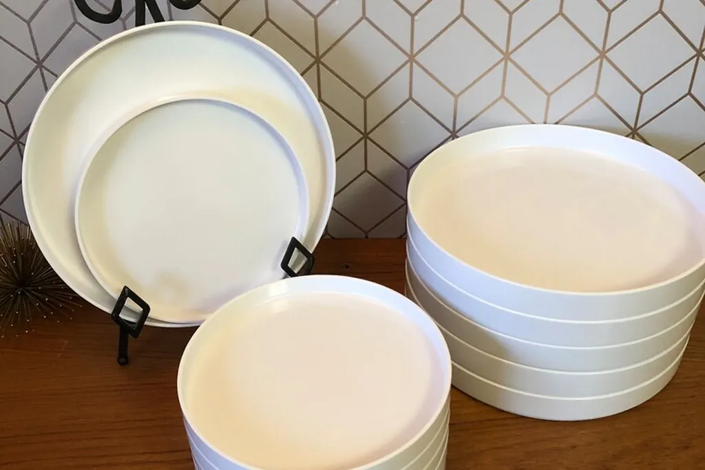 Stacks of white serving bowls and plates on a wood surface.