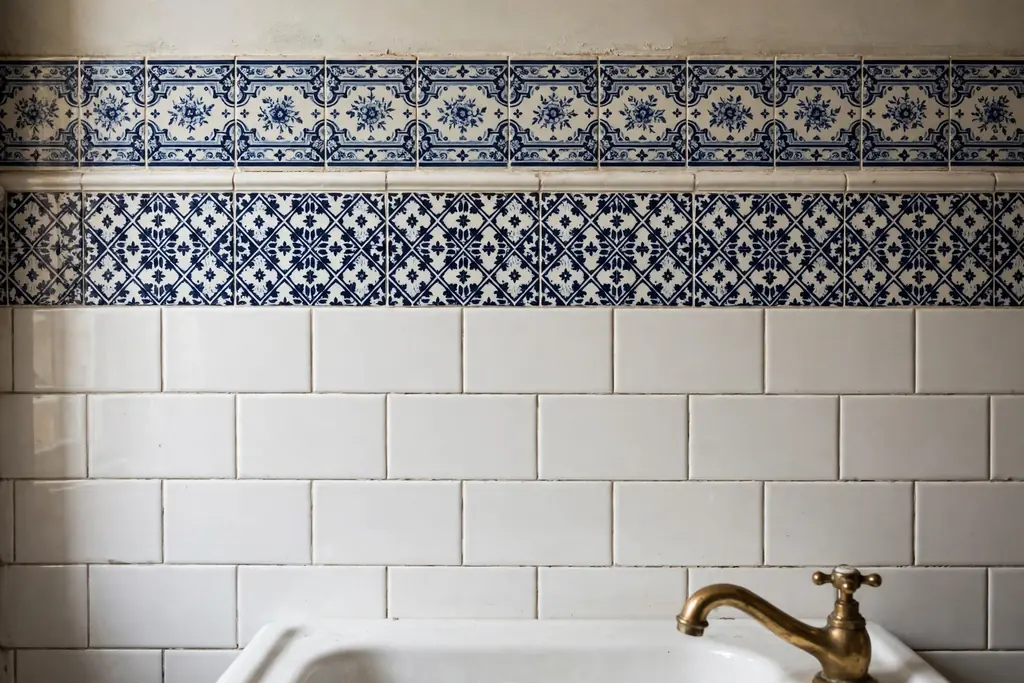 Decorative tile border trim running above white subway tile in a bathroom