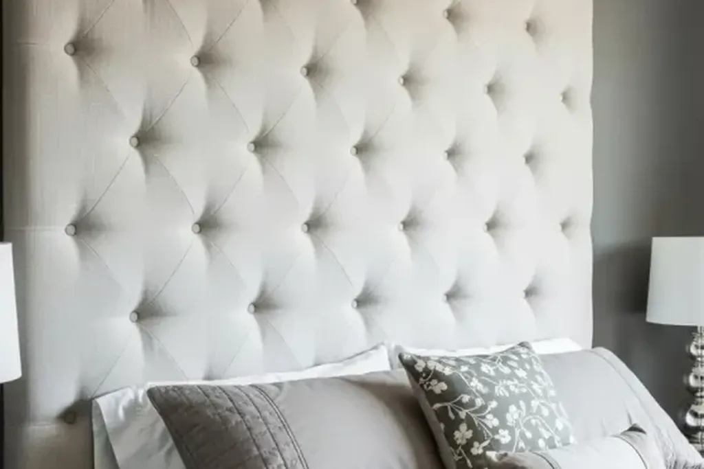Bed with a padded headboard and cushions behind the pillows.