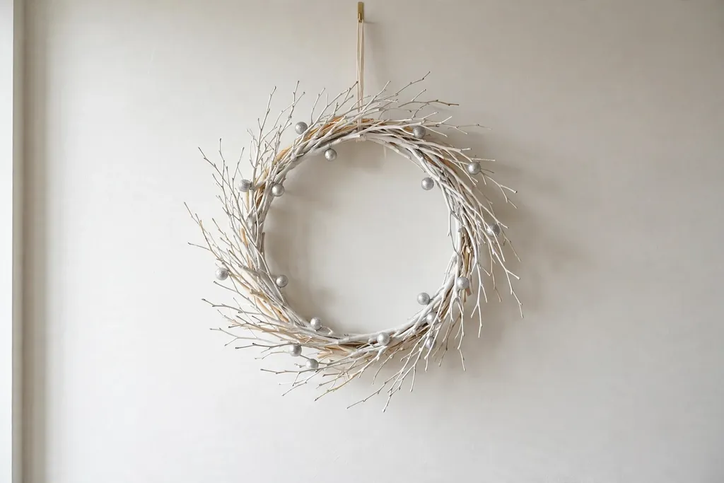 White and silver wreath with pale branches on a light wall